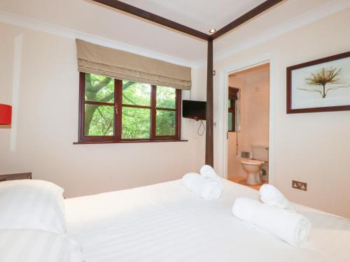 a bedroom with a bed with white sheets and a window at Clematis - Lodge 16 in Wadebridge