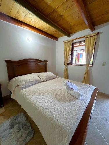 a bedroom with a large bed with white sheets and a window at CASA VACACIONAL SAN MARCOS in Villa de Leyva