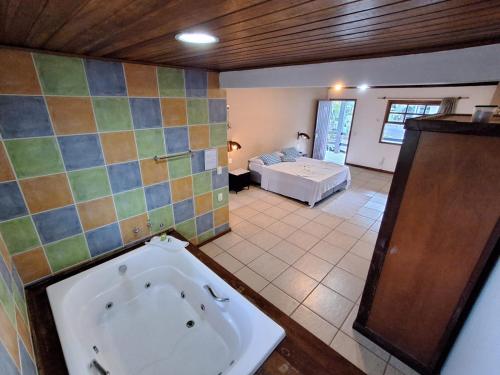 a bathroom with a bath tub and a bedroom at Pousada Nova Conquista in Penedo