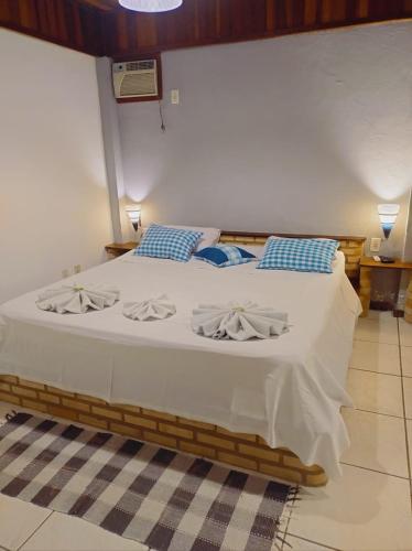 a bedroom with a bed with white sheets and blue pillows at Pousada Nova Conquista in Penedo