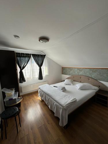 a bedroom with a large white bed and a window at Casa David in Buşteni