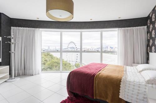 a bedroom with a bed and a large window at Lindo Apto no Terraços da Rainha in Balneário Camboriú