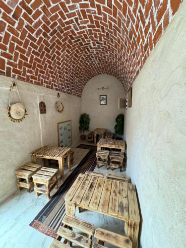 a room with wooden tables and a brick wall at Dar alibaba in Douz