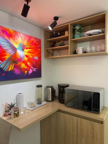 a kitchen with a microwave and a painting of a bird at Aero Hotel Boutique in Bogotá