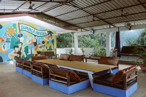 a table and chairs in front of a mural at Summer Hostel in Palolem