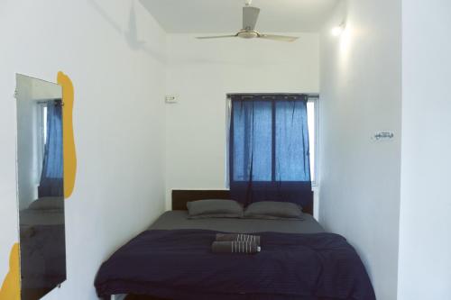 a bed in a white room with two windows at Summer Hostel in Palolem