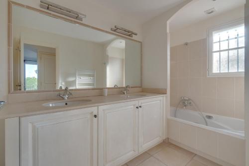 une salle de bain avec deux lavabos, un miroir et une baignoire dans l'établissement Les Villas de Saint Endréol, à La Motte