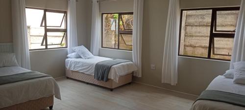 Un dormitorio con dos camas y dos ventanas. en Sunshack, en Port Shepstone