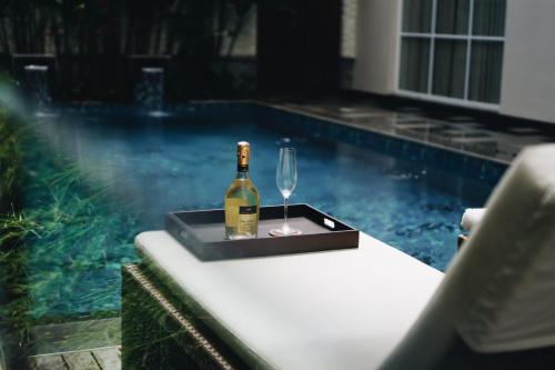 a bottle of wine and a glass on a table next to a pool at Kula Kara Villas Uluwatu in Uluwatu