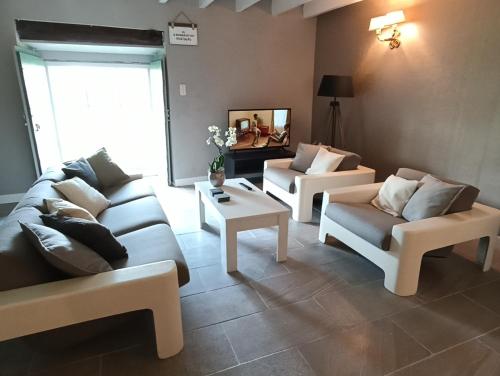 un salon avec deux canapés et une télévision dans l'établissement Le Bonheur du Périgord - Gîte, à Mialet