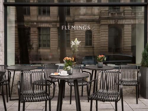 a group of tables and chairs in front of a building at Flemings Hotel München-City in Munich