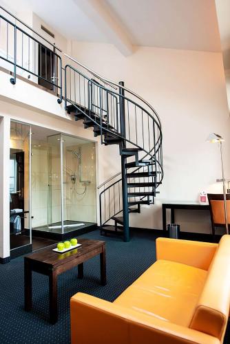 a living room with a yellow couch and a spiral staircase at Flemings Hotel München-City in Munich