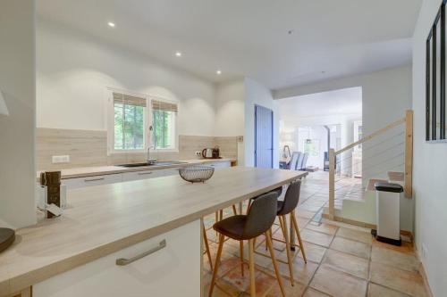 une cuisine avec un grand comptoir en bois et des chaises dans l'établissement VILLA rénovée, piscine vue mer, clim, borne VE, à Roquebrune-sur Argens