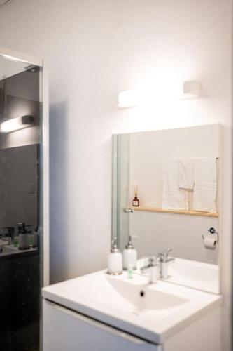 une salle de bain blanche avec un lavabo et un miroir dans l'établissement Appartement 21 - Lumineux - Paisible - Proximité Lac et Parcs, à Vichy