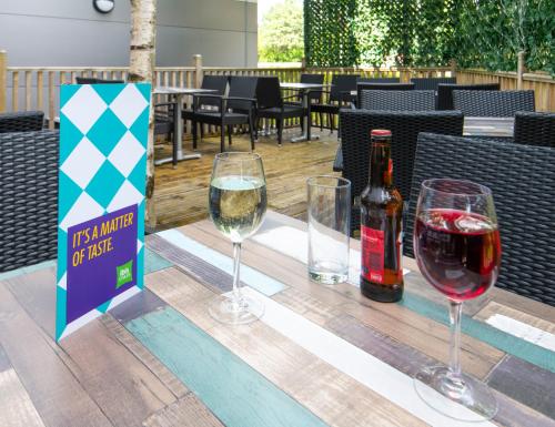 two glasses of wine and a bottle on a table at ibis Styles Haydock in Haydock