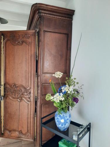 a vase with flowers on a table next to a door at GITE CHEZ BERTHE in Pontfarcy