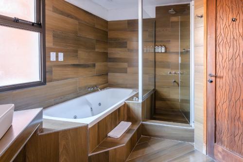 a bathroom with a tub and a glass shower at Lares De Chacras in Chacras de Coria