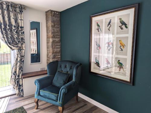 a blue room with a chair and a picture of birds at The Lodge by Cefn Tilla in Usk