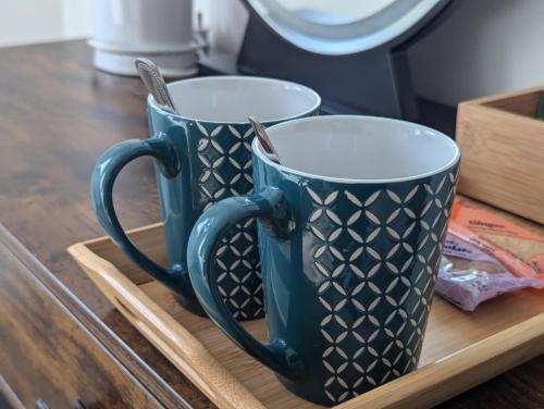 two blue cups sitting on a wooden tray at The Lodge by Cefn Tilla in Usk