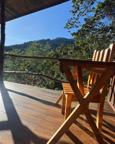 two wooden chairs sitting on a deck with a view at El Toucanet Lodge & Restaurante in El Copey