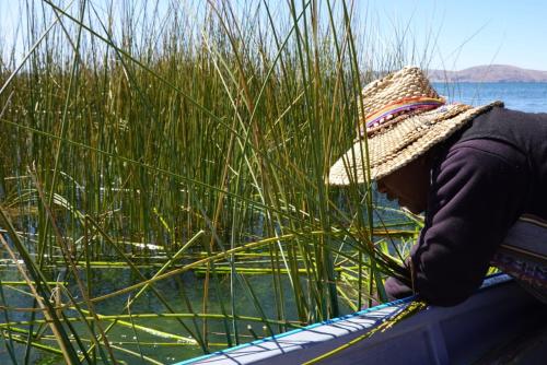 a person wearing a straw hat sitting on a boat at Uros Lake Titicaca Lodge in Puno