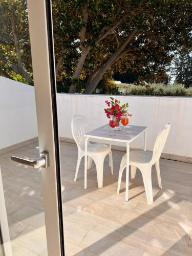 a table with two chairs and a table with flowers on it at Villa Aurea in Ispica