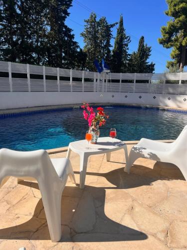 a table with flowers on it next to a swimming pool at Villa Aurea in Ispica