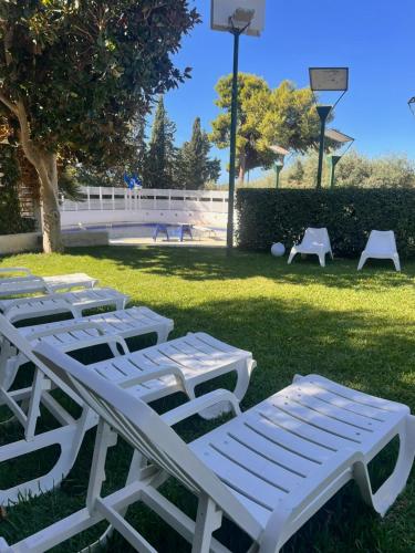 a group of white lounge chairs sitting in the grass at Villa Aurea in Ispica