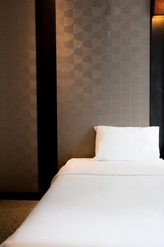 a bed with a white pillow in a room at Sukhothai Hotel and Residence Ratchada in Bangkok