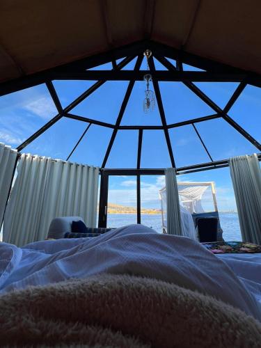 a bedroom with a view of the ocean through a window at Uros Lake Titicaca Lodge in Puno