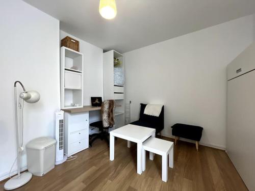 Cette chambre blanche dispose d'un bureau, d'une table et de chaises. dans l'établissement Le Studio des Sablons-2 pers-150m place du marche, à Fontainebleau