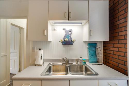 - une cuisine avec un évier et un mur en briques dans l'établissement Quaint Mt Vernon Cottage Near Historic Dtwn!, à Mount Vernon