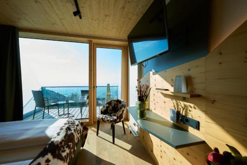 a bedroom with a bed and a tv and a balcony at Bergwelt Kandel Hotel & Eventlocation in Waldkirch
