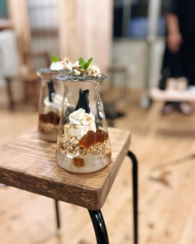 two desserts in a glass jar on a wooden table at 'Yamaneko Hotel 'Saunas, Serenity & Feline Friends in Miyoshi