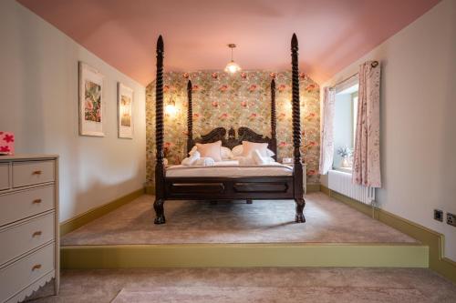 Schlafzimmer mit Himmelbett und Fenster in der Unterkunft The Maze Garden Cottage by Mint Stays in Biddlestone