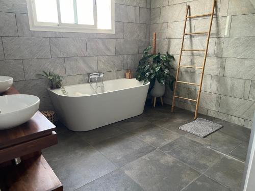 a bathroom with a white bath tub and a ladder at Villa Étang salé les bains avec piscine privée in Étang-Salé les Bains