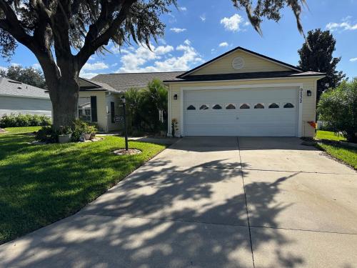 a house with a white garage and a tree at Delia Place Florida Oasis With Private Lanai in The Villages