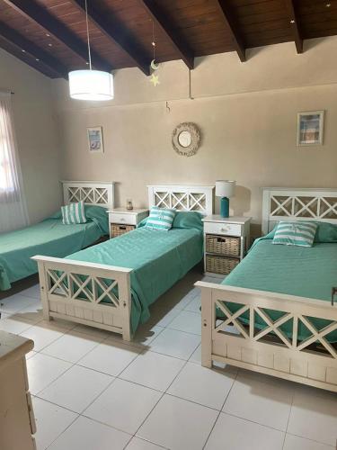 two beds in a room with green sheets at la Casita del bosque in Villa Gesell