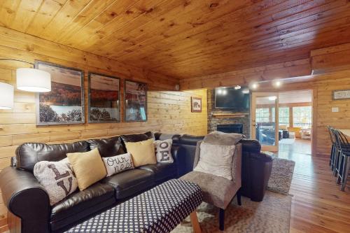 a living room with a leather couch and wooden walls at Lakeview Hideaway in Ellijay