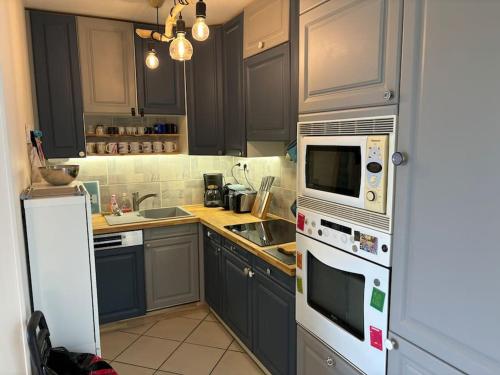 une cuisine avec des placards gris et des appareils blancs dans l'établissement Carré d'or Res Edelweiss 4 Pers avec parking, à Le Touquet-Paris-Plage