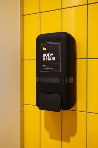 a soap dispenser on a yellow tiled wall at Little Monkey Hostel in Enschede