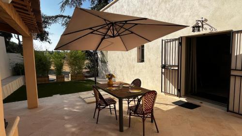 une table avec des chaises et un parasol sur une terrasse dans l'établissement Un Cottage au pied du Ventoux, à Bédoin