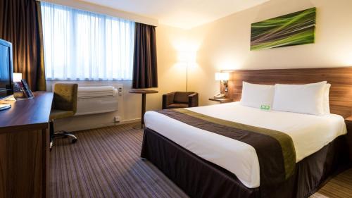a hotel room with a bed and a desk at Holiday Inn Slough Windsor by IHG in Slough
