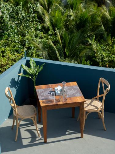 a wooden table and two chairs sitting next to a table at La Pearl Mathiveri in Mathiveri
