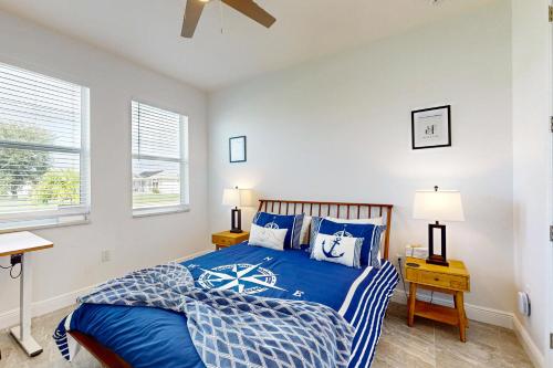 a bedroom with a blue bed and two windows at Bliss Bungalow in Cape Coral