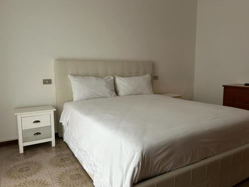 a bedroom with a white bed and a night stand at Ranco Lake Sunshine Apartment in Ranco