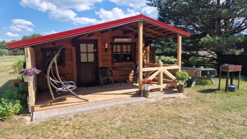 a small wooden cabin with a red roof at SP camping Spāres Prieduļi in Nīca