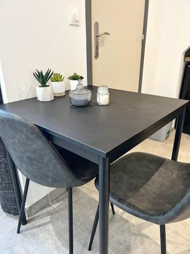 une table noire avec deux chaises et des plantes en pot dans l'établissement Studio tout équipé avec parking, à La Rochelle