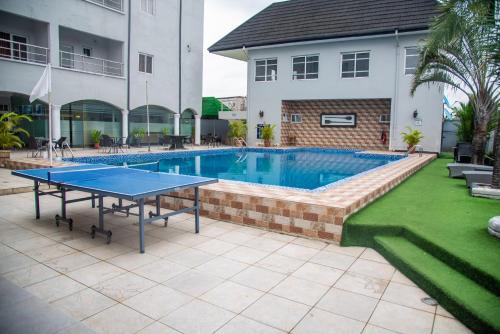 a swimming pool with a ping pong table in front of a house at Golden Tulip Hotel -GT31 Stadium Road in Port Harcourt