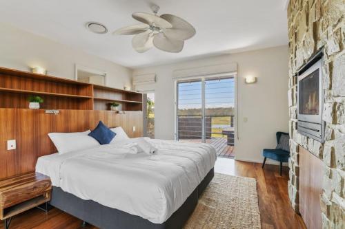 a bedroom with a large bed and a ceiling fan at Mountain Majesty with Poolside Relaxing Getaway in Tamborine